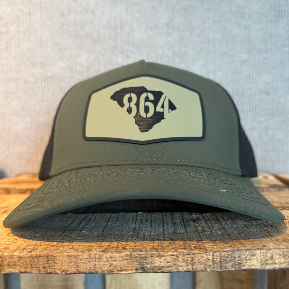 Green and black cap with a '864' in South Carolina map logo patch on wood surface